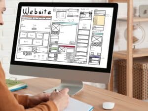 Person creating a wireframe layout for a website redesign on a desktop computer.