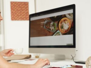 Person browsing a food website on a desktop, showcasing mobile web page design for restaurant optimisation.