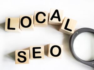 "Local SEO" spelled out with wooden blocks and a magnifying glass, highlighting the need for tradies to optimize their website for local search.