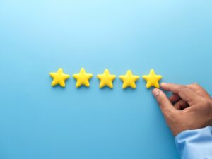 A hand adds a fifth yellow star to a row, showing five stars. Dental website stand out with top reviews.