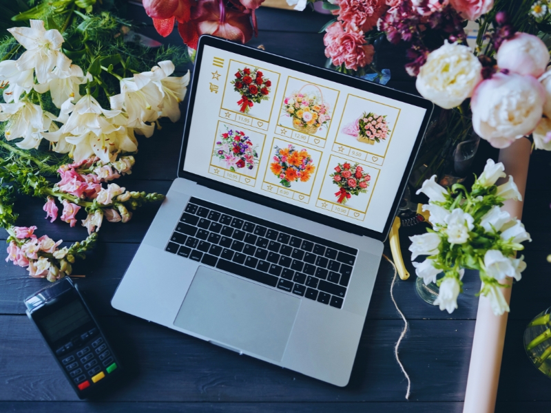 Florist shop using website personalisation to display flower bouquet options on a laptop surrounded by fresh blooms.