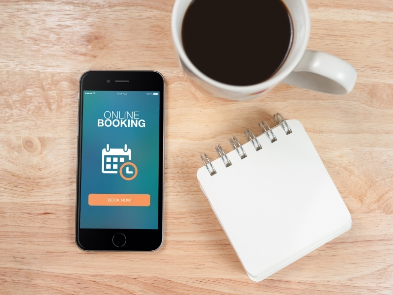 Cafe website design for mobile booking shown on smartphone beside coffee cup and notepad.