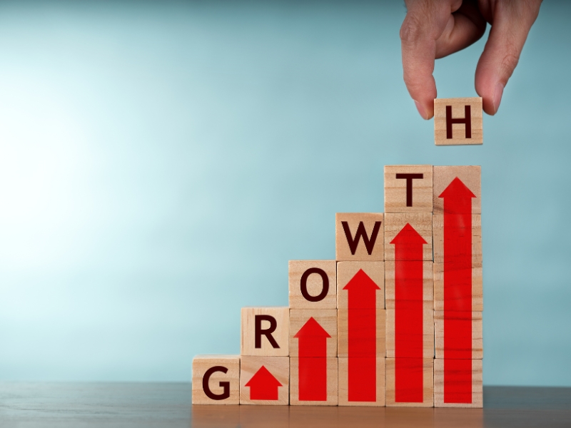 Business growth program concept with stacked blocks spelling growth and red arrows upward.