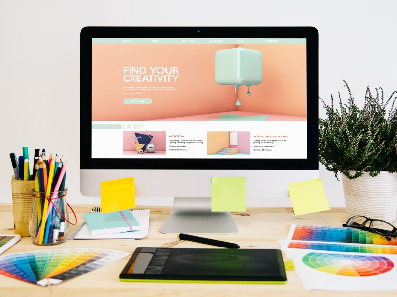 Creative workspace showing custom website design packages with colour palettes, pencils, and responsive layouts.