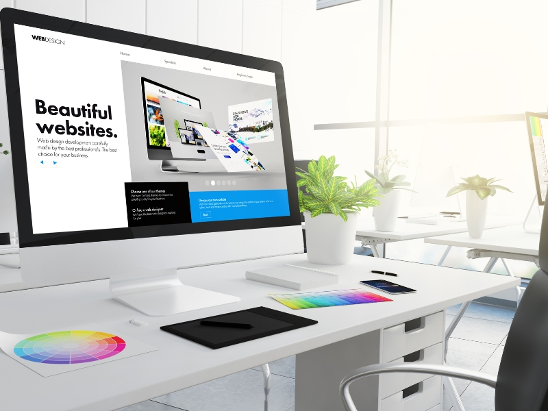Computer monitor displaying modern web layouts and colour palettes, representing creative web design for manufacturing businesses.